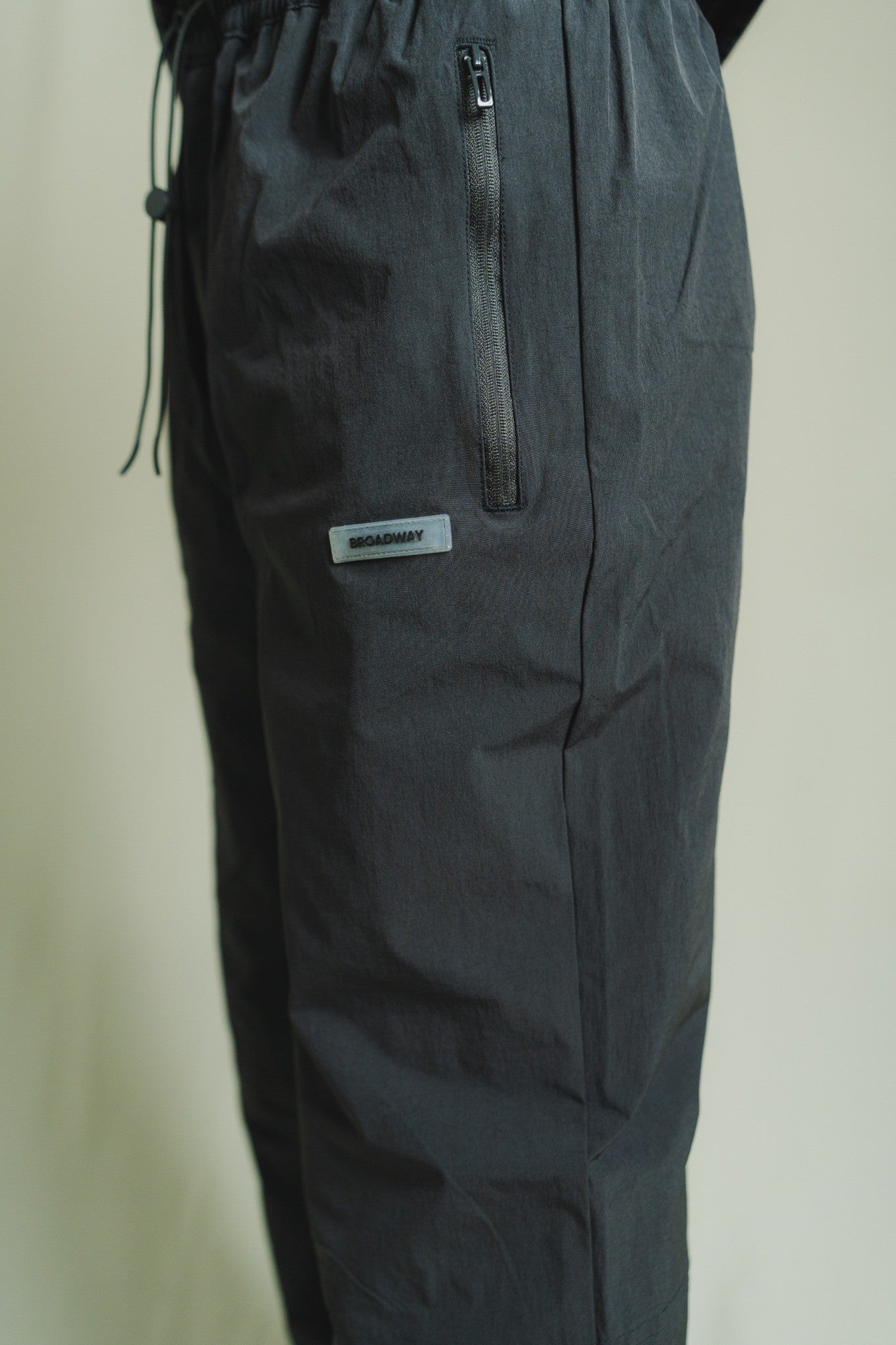 Dark gray pants with a brand label on a light beige background