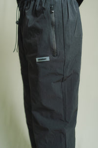 Dark gray pants with a brand label on a light beige background