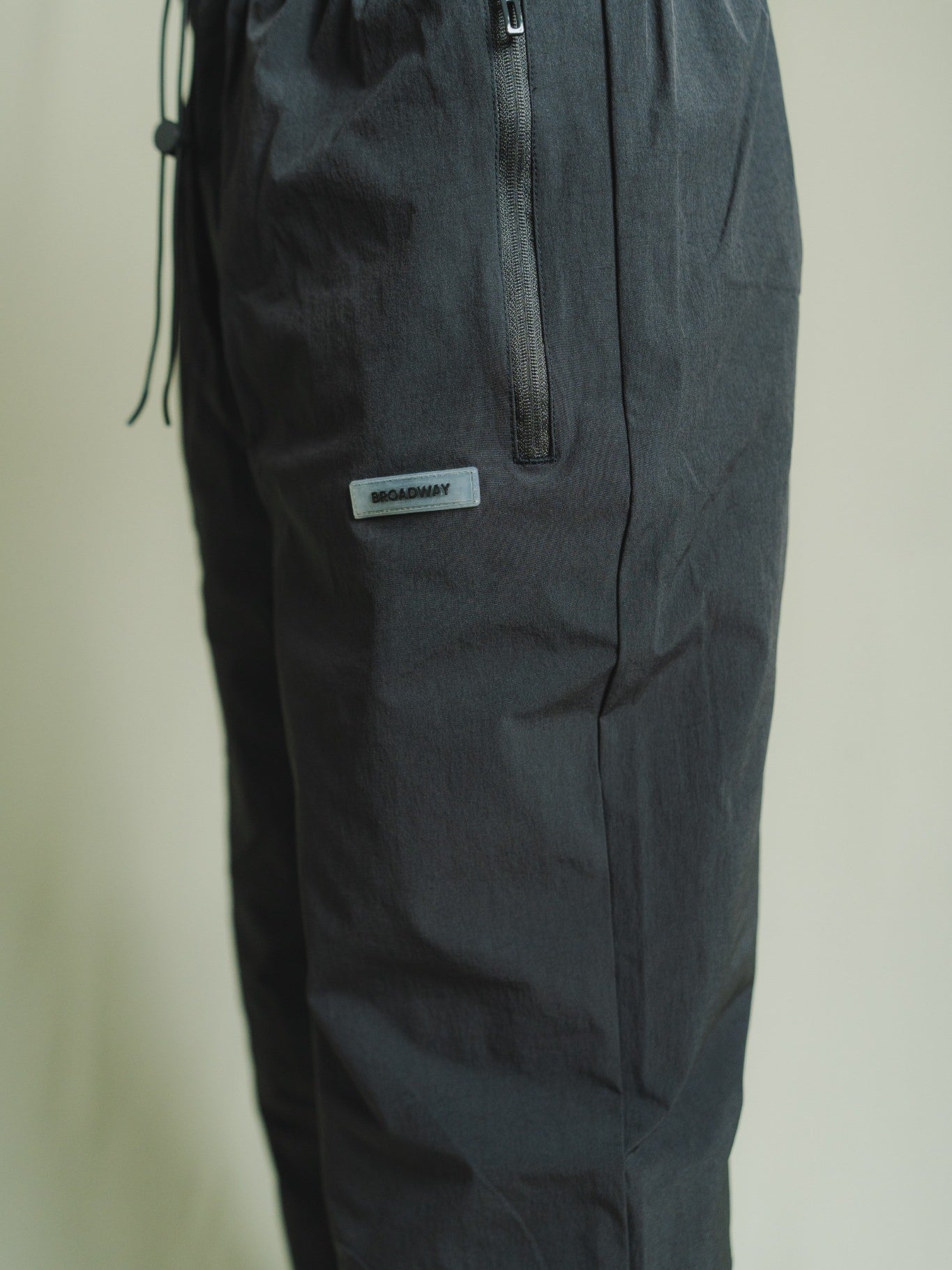 Dark gray pants with a brand label on a light beige background