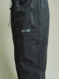 Dark gray pants with a brand label on a light beige background